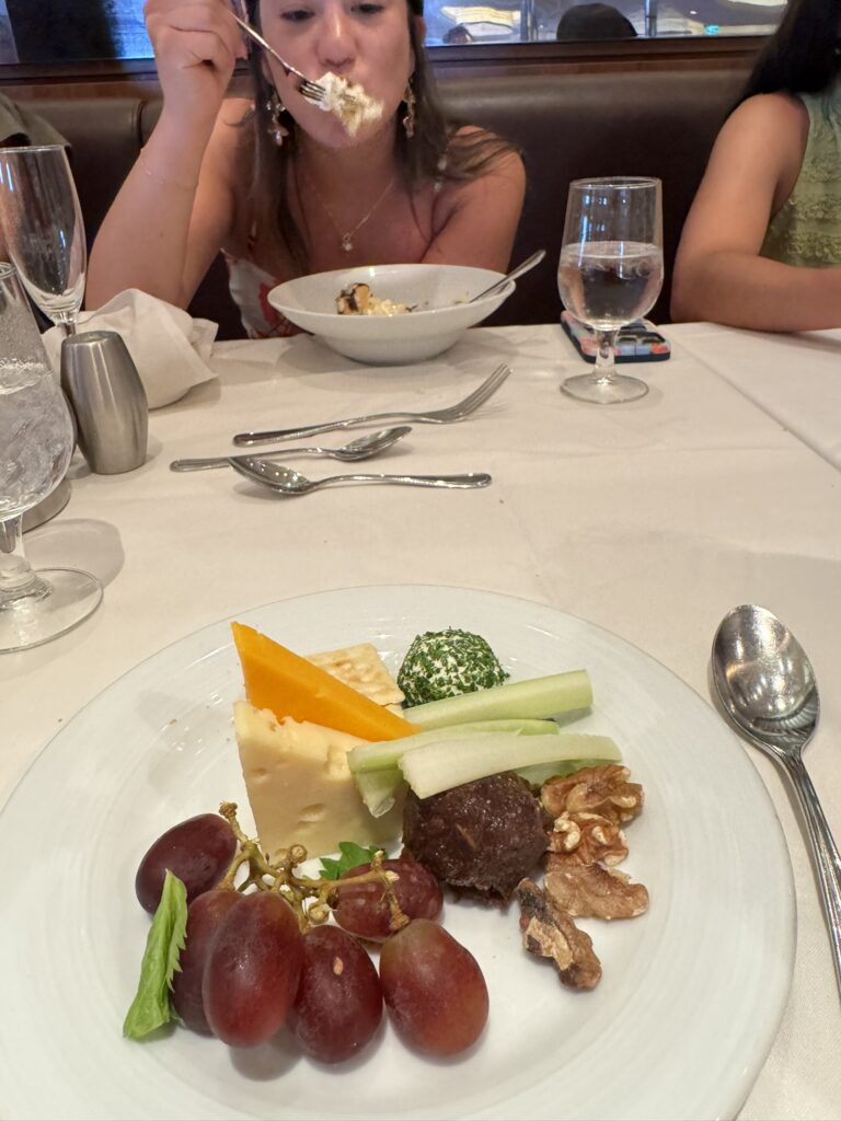 Plate with cheese, grapes, and a few simple veggies, representing an easy appetizer option for picky eaters on a cruise.