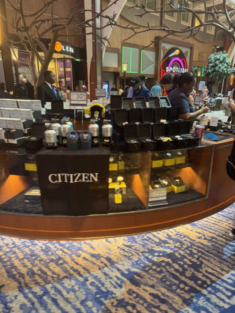 Guests browsing Citizen watch displays during onboard shopping events on a cruise, featuring promotional sales and brand showcases