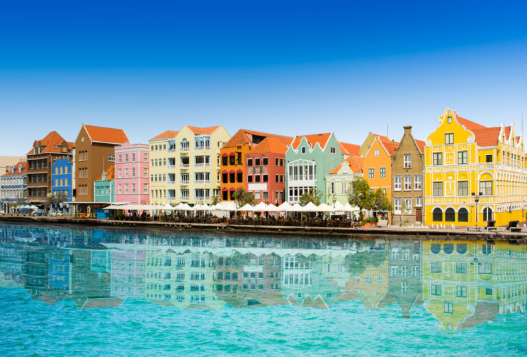 Colorful waterfront buildings along the Willemstad embankment in Curaçao with views of the historic harbor