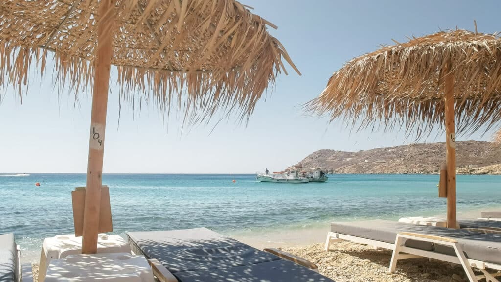 beach chairs and fishing boat at elia beach on mykonos, greece
