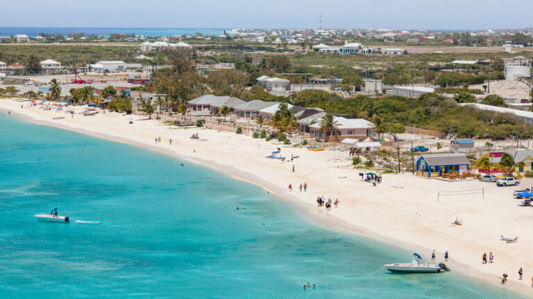 Beach and pool area at the Grand Turk Cruise Center with turquoise water, loungers, and cruise ships docked nearby