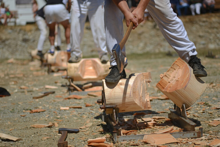 Competitors chopping logs with axes during a lumberjack wood‑chopping event.