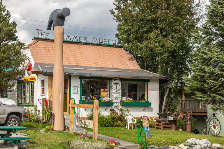 Exterior view of the Hammer Museum in Haines, Alaska, featuring the giant hammer sculpture and rustic building that mark this quirky local attraction.