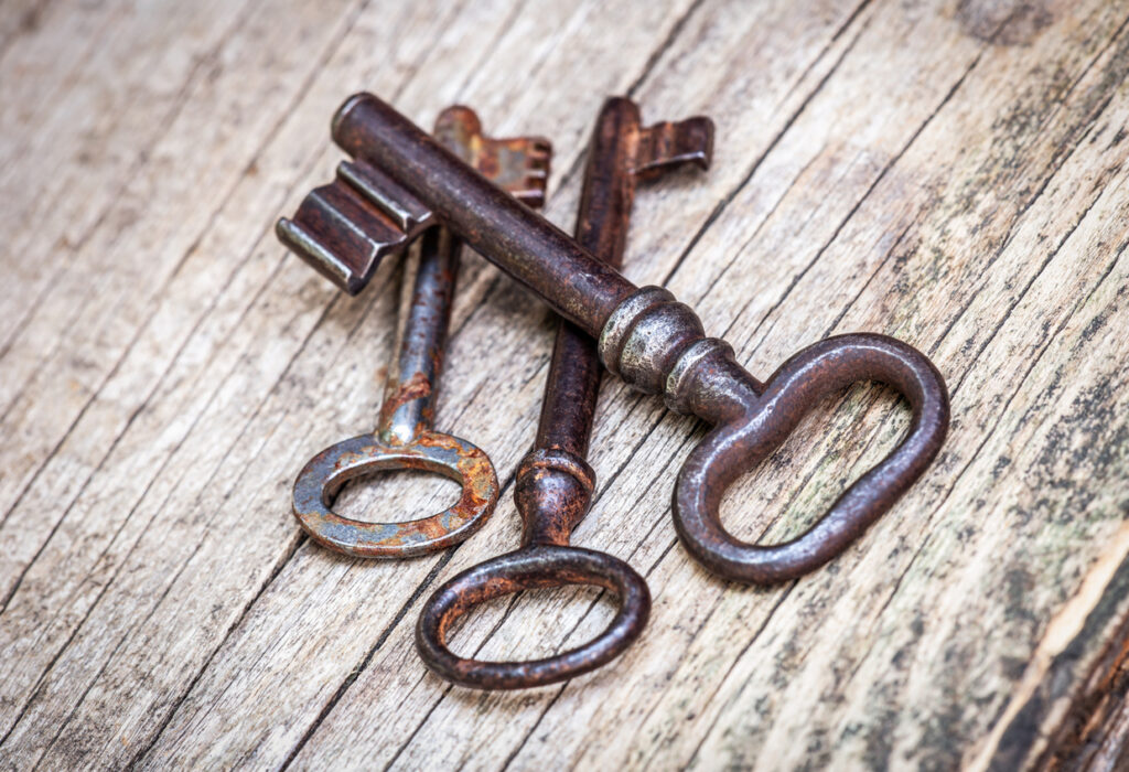 Antique metal keys resting on weathered wood, symbolizing historic locks and old island architecture.
