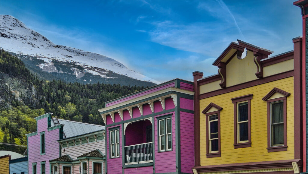 Colorful Gold Rush–era buildings in historic downtown Skagway, Alaska, with false‑front architecture set against the surrounding mountains.