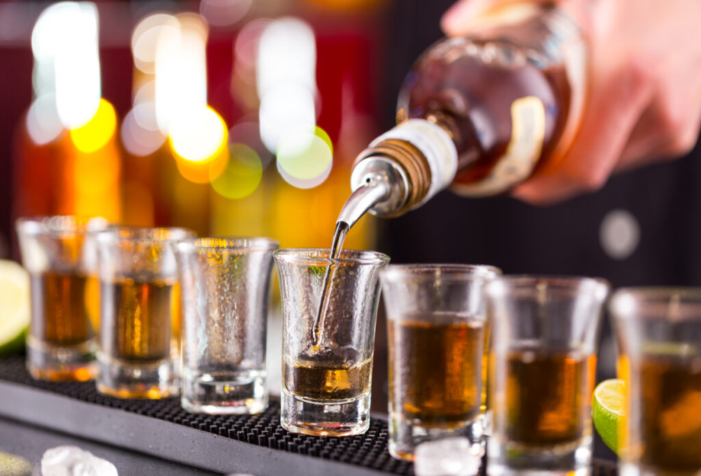 Bartender pouring rum into shot glasses, representing the tasting experience at John Watling’s Distillery in Nassau