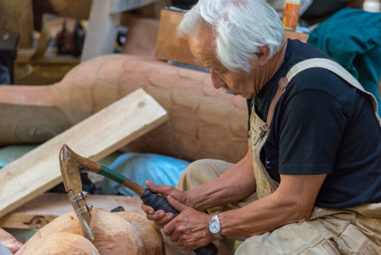 Alaska Native artists demonstrating traditional carving and cultural arts during an outdoor event in Alaska.