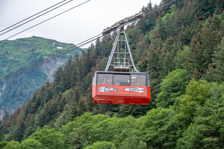 Red Mount Roberts Tramway cabin traveling above a forested mountainside in Juneau, Alaska.