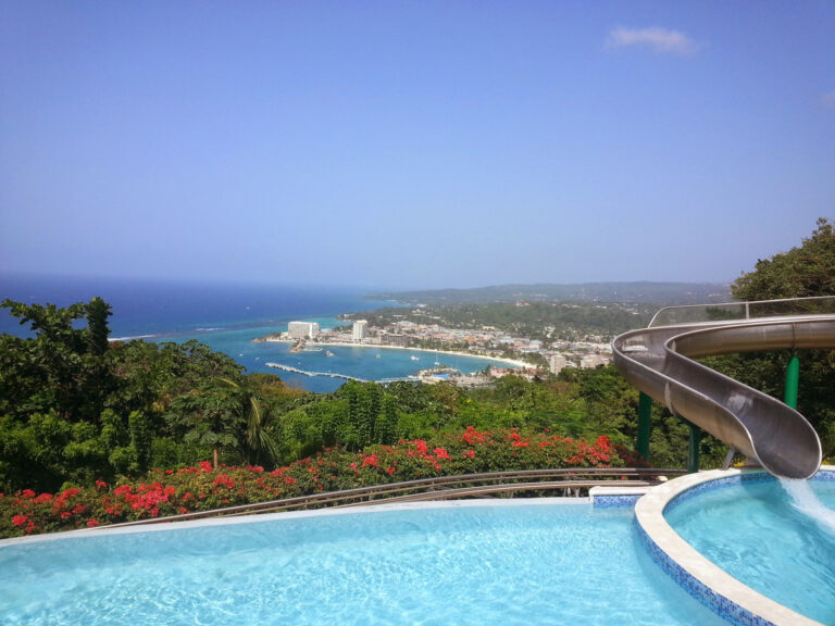 Panoramic view of Ocho Rios and the Caribbean Sea as seen from the top of Mystic Mountain, with lush rainforest in the foreground.