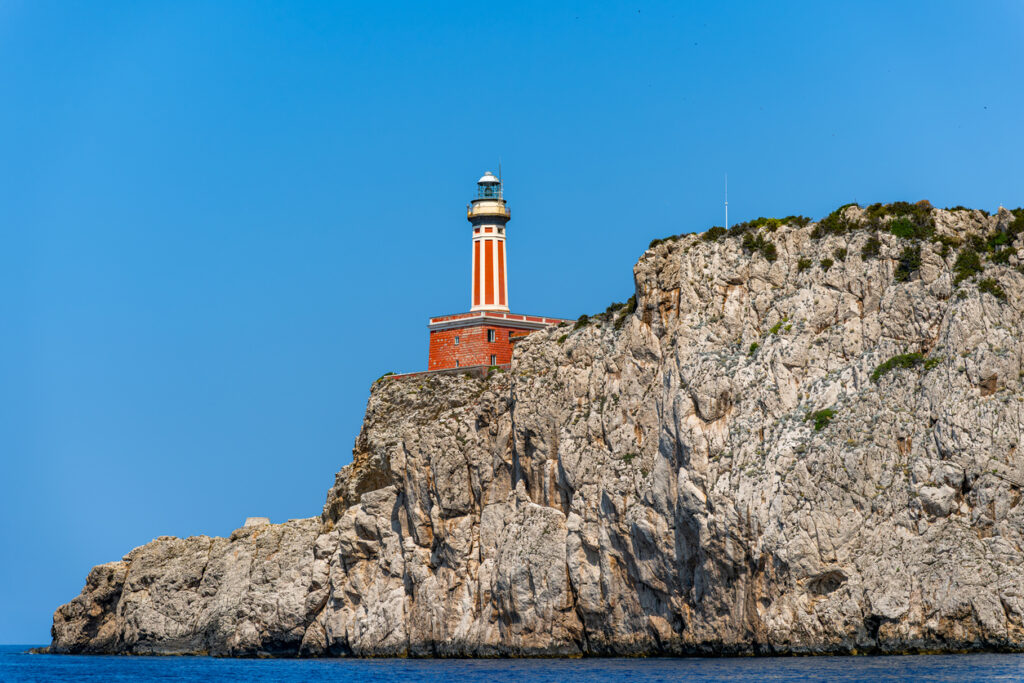 Punta Carena Lighthouse on Capri with rocky coastline and turquoise Mediterranean water