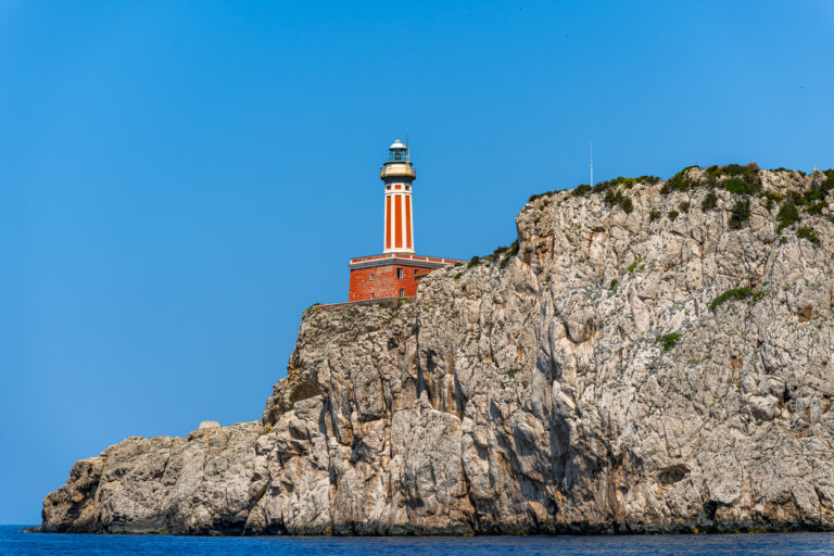 Punta Carena Lighthouse on Capri with rocky coastline and turquoise Mediterranean water