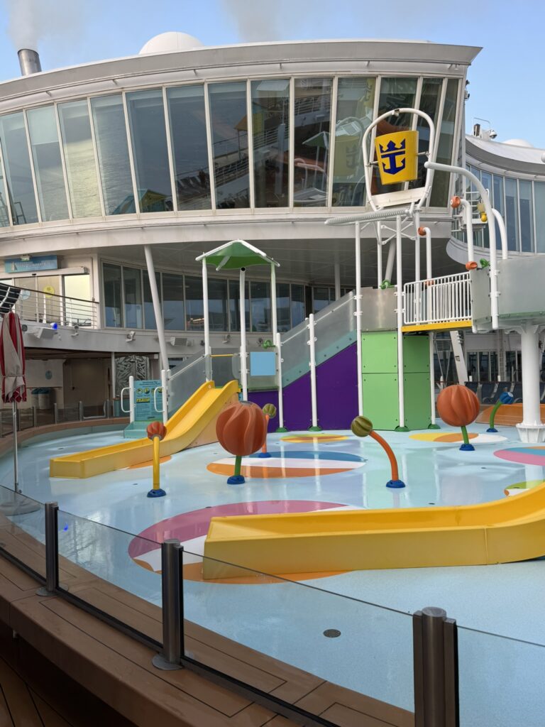 Colorful kids water play area on a Royal Caribbean ship with small slides, sprayers, and a shallow splash zone
