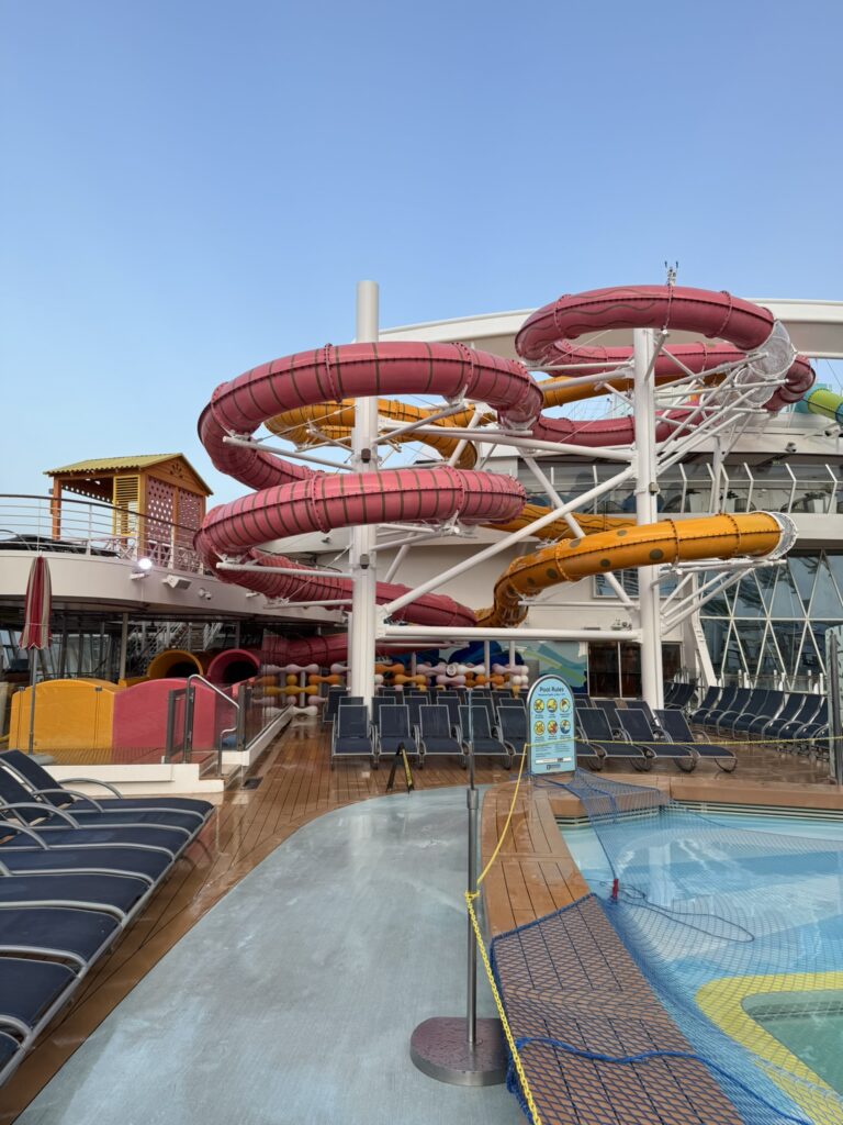 Colorful water slides and kids’ pool area on a Royal Caribbean ship with lounge chairs and shallow play spaces