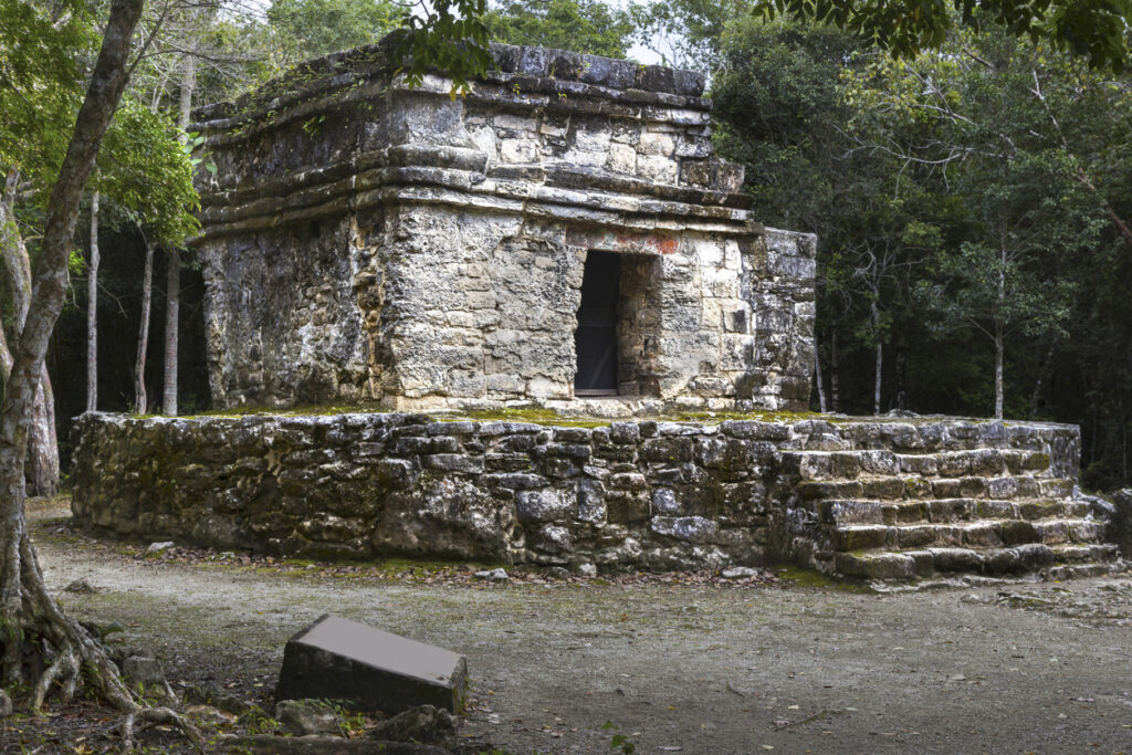 Ancient stone temple at San Gervasio Mayan Ruins surrounded by dense jungle on Cozumel Island.
