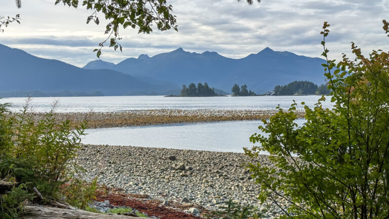 View of Sitka Sound from Sitka National Historical Park, with small forested islands, distant mountains, and coastal vegetation along the shoreline.