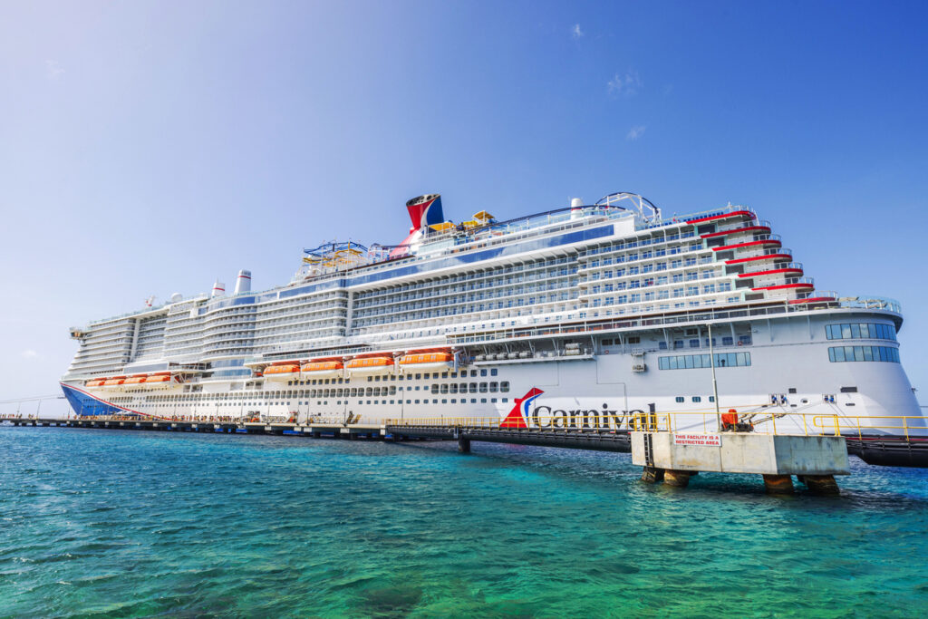 Carnival cruise ship docked in turquoise Caribbean water near the Willemstad pier under a clear blue sky