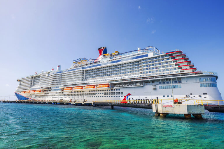 Carnival cruise ship docked in turquoise Caribbean water near the Willemstad pier under a clear blue sky