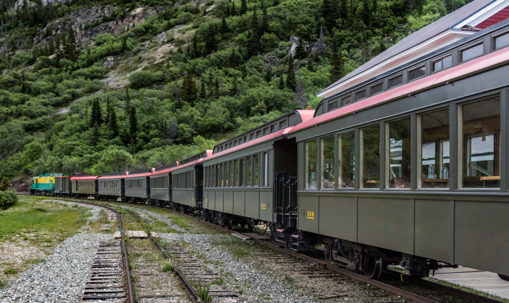 White Pass and Yukon Route Railway train traveling from Skagway, Alaska, toward Carcross in Canada’s Yukon Territory, passing through rugged mountains and historic Gold Rush scenery.